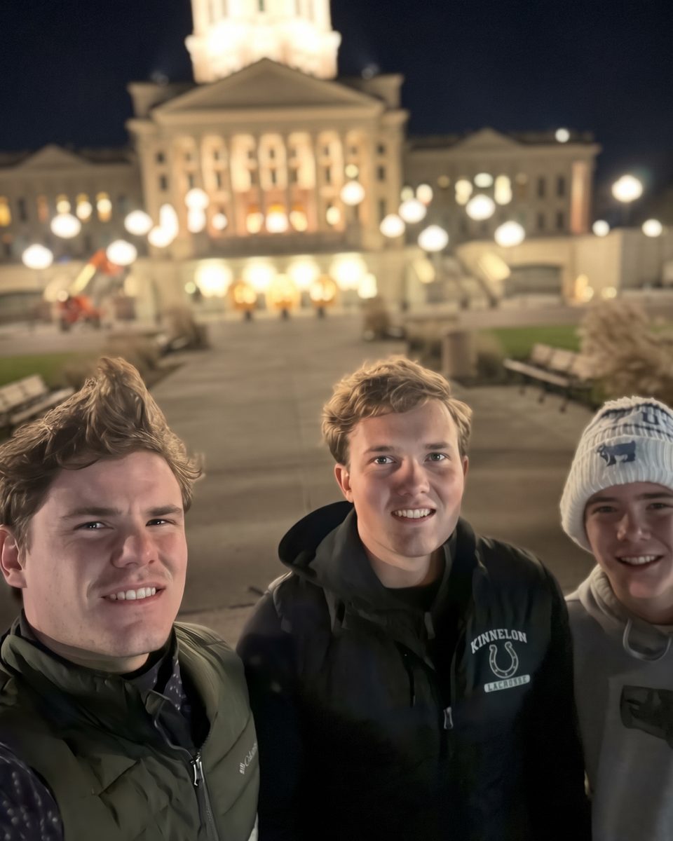 The three brothers who founded Hill City Estate Services, smiling together outdoors at night